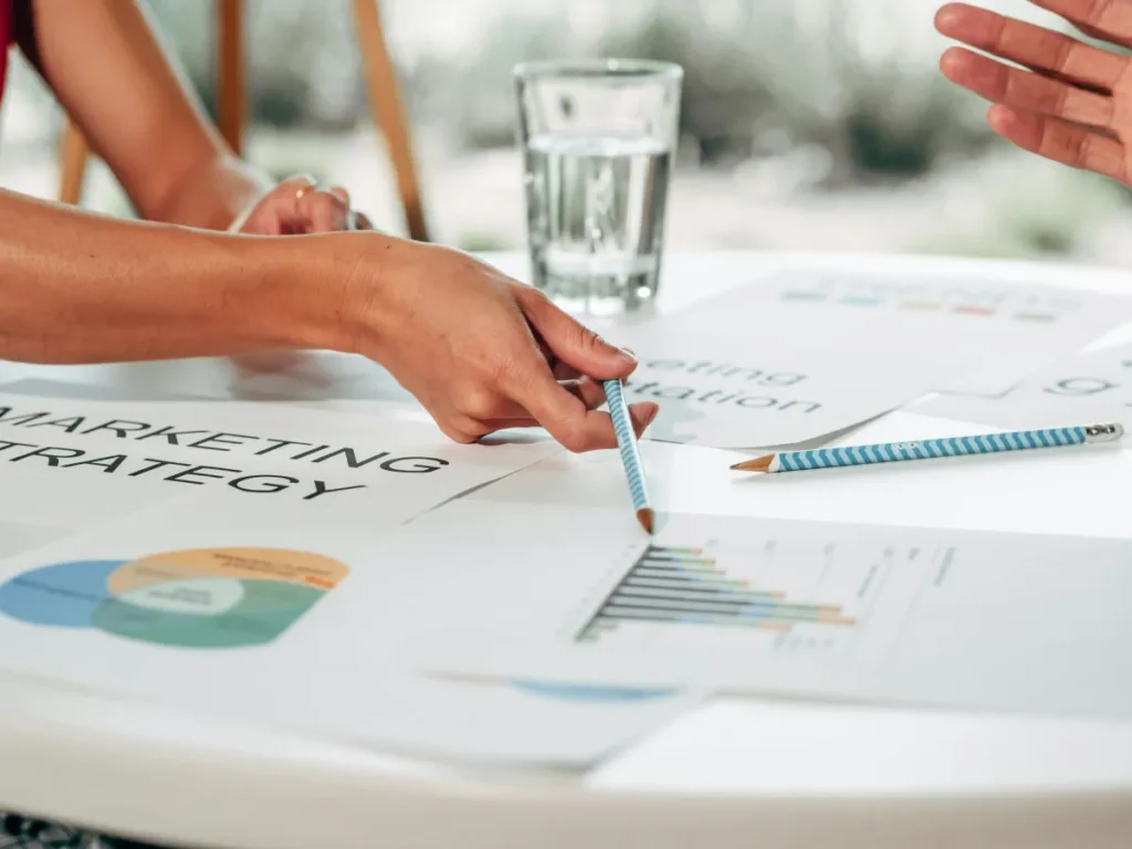 Tim profesional mendiskusikan strategi pemasaran dengan grafik dan diagram di meja rapat